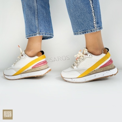 Ténis brancos com detalhes amarelo, rosa e castanho usados com calças de ganga azuis