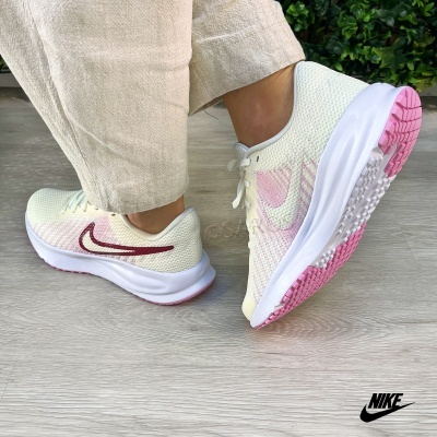 Ténis desportivos Nike em malha branca com detalhes rosas e bordeaux em pé e a vista da sola rosa