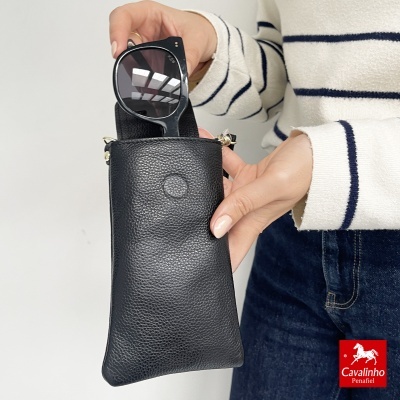 Bolsa preta de couro com óculos de sol redondos e pessoas a segurar, fundo branco.