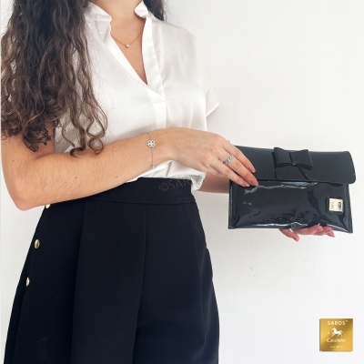 Carteira preta brilhante com laço e mulher vestindo branco e preto