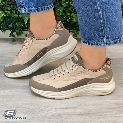 Ténis Skechers bege e cinza com padrão animal print e sola branca em piso de madeira clara