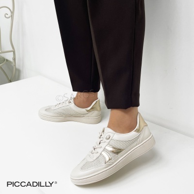 Ténis femininos brancos e dourados com textura de malha e calças pretas num fundo branco