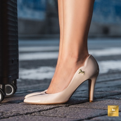 Sapatos de salto alto nude de verniz com detalhe metálico dourado e mala preta ao lado