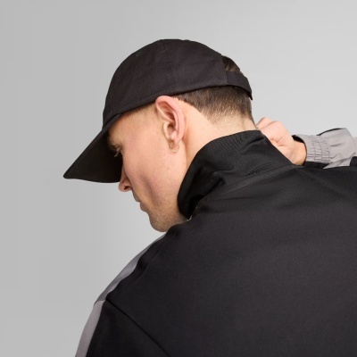 Pessoa de costas com boné preto e casaco preto com detalhes cinzentos