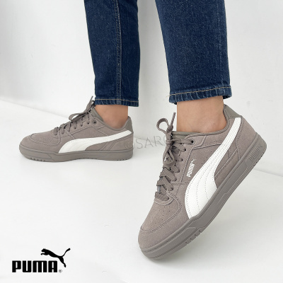 Ténis Puma cinza com risca branca usados com calças de ganga