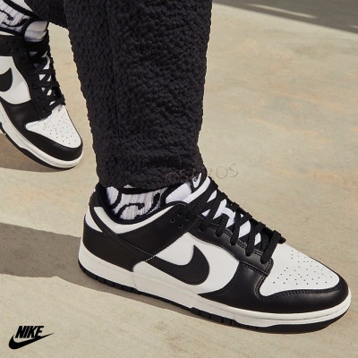 Ténis Nike preto e branco com logótipo visível, usados com meias brancas e pretas e calças pretas