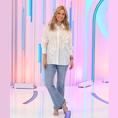 Mulher com camisa branca com flores e jeans azuis claros em estúdio iluminado