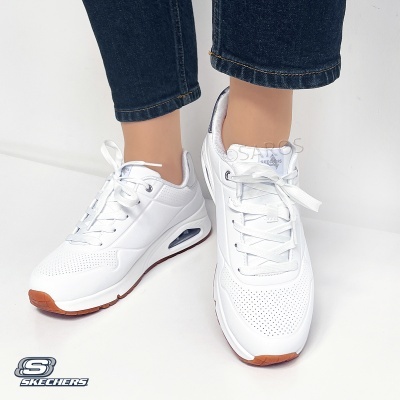 Sapatilhas brancas Skechers com sola castanha e branca usadas com calças de ganga azul