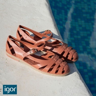 Sandálias de plástico cor de rosa com fivela junto a piscina azul