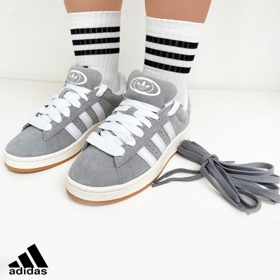 Ténis Adidas cinzentos com riscas brancas e atacadores, meias brancas com riscas pretas