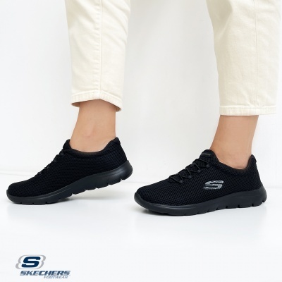 Sapatilhas pretas Skechers com sola preta e logo cinzento, calças bege
