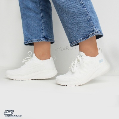 Sapatilhas brancas Skechers de tecido malha com sola branca usadas com jeans azuis