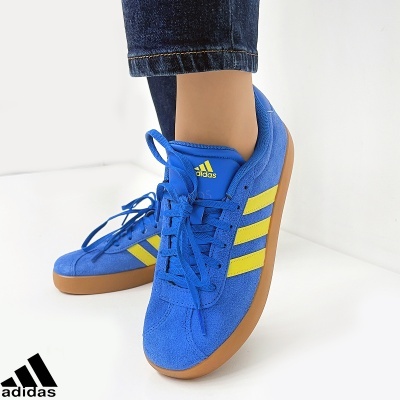Tênis Adidas azuis com riscas amarelas e sola castanha