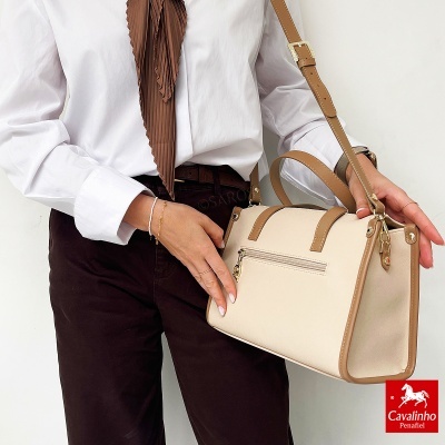 Mala bege com detalhes castanhos e alça ajustável, roupa branca e castanha, fundo branco