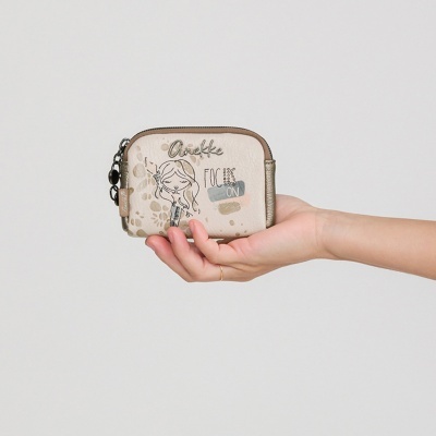 Carteira pequena bege com ilustração e texto Anekke, segurada por mão feminina