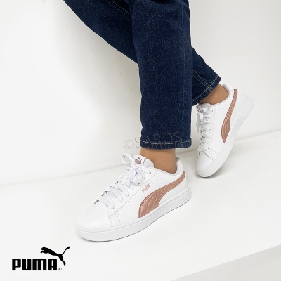 Ténis Puma brancos com risca lateral bronze metálico usados com jeans azuis escuros