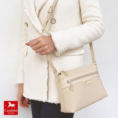 Bolsa bege claro com alça e detalhes dourados, usada com casaco bege claro texturizado