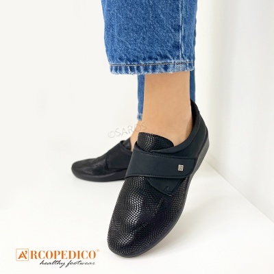 Sapatos pretos texturizados com tira elástica e sola preta, usados com calças de ganga azuis