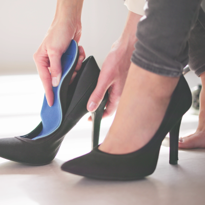 Pessoa a colocar uma palmilha azul num sapato de salto alto preto