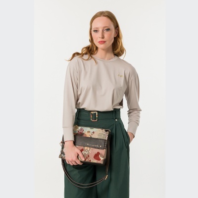 Mulher com roupa bege e verde segurando carteira estampada colorida
