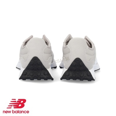 Ténis desportivos cinza claro New Balance vistos por trás com solas branco e preto.