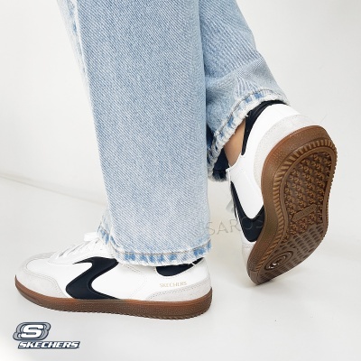 Ténis Skechers brancos com detalhes em preto e sola castanha usados com calças de ganga azul claro