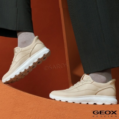 Ténis Geox bege com sola branca em fundo laranja