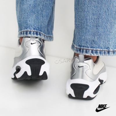 Ténis NIKE prata, branco e preto vistos de trás com calças de ganga azuis