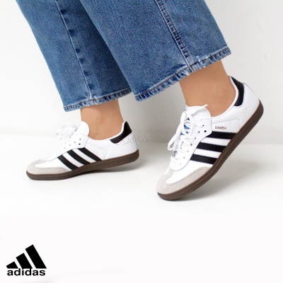 Ténis Adidas Samba brancos com riscas pretas e sola castanha.
