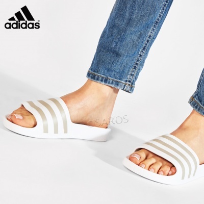 Chinelos Adidas brancos com riscas cinzentas e calças de ganga azuis