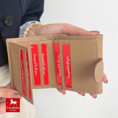 Carteira castanha clara aberta com cartões vermelhos nas mãos