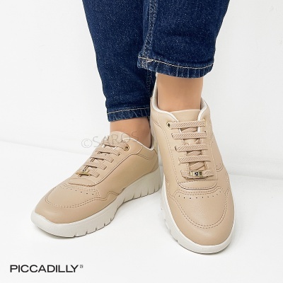 Ténis femininos bege com sola branca e cadarços, usados com calças de ganga.