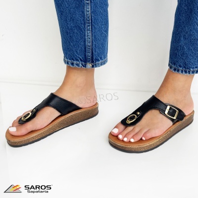 Sandálias de dedo pretas com fivela dourada usadas por pessoa com calças de ganga azul