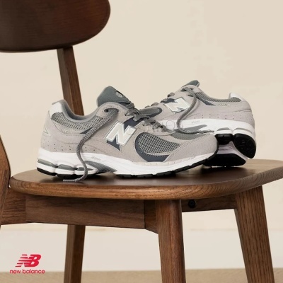 Sapatilhas New Balance 2002R cinza sobre cadeira de madeira