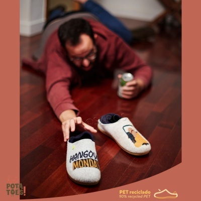 Calçado tipo chinelos cinzentos com frases bordadas e interior azul.