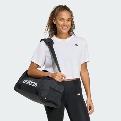 Mulher com t-shirt branca, leggings pretas e mala de desporto preta Adidas