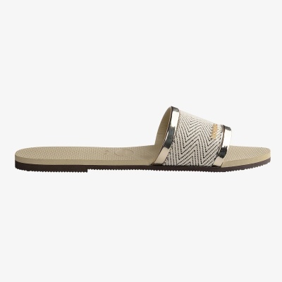 Chinelo slide bege com padrão zig-zag e detalhes metálicos dourados