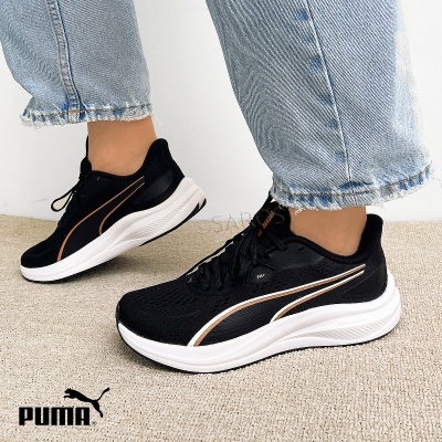 Ténis Puma pretos com sola branca e detalhes dourados usados com calças de ganga claras