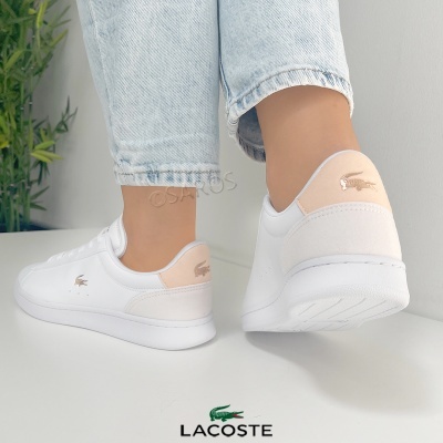 Ténis brancos Lacoste com detalhes bege e logo crocodilo, usados com jeans claros