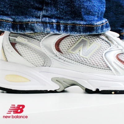 Ténis New Balance cinzento e branco com sola espessa e jeans azul