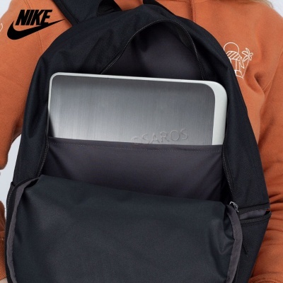 mochila preta Nike com dispositivo prateado SAROS dentro, usada por pessoa com casaco cor de ferrugem