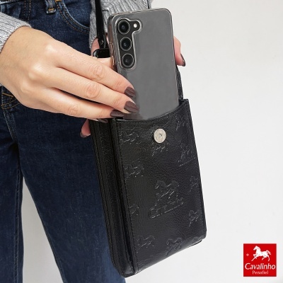 Bolsa preta em pele com padrão de cavalos, telemóvel e mão segurando