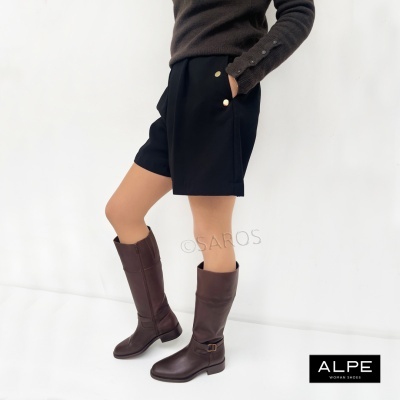 Botas castanhas de couro com calções pretos e camisola castanha escura.