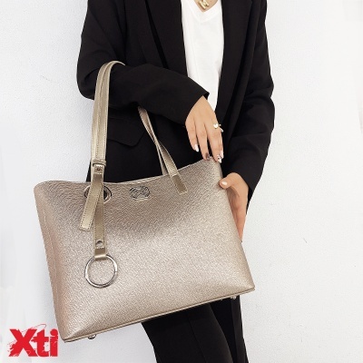 Mala dourada metálica com argola prateada segurada por pessoa vestindo preto