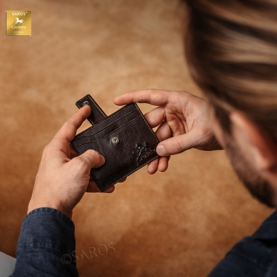 Carteira pequena em pele castanha escura com fecho de botão nas mãos de um homem