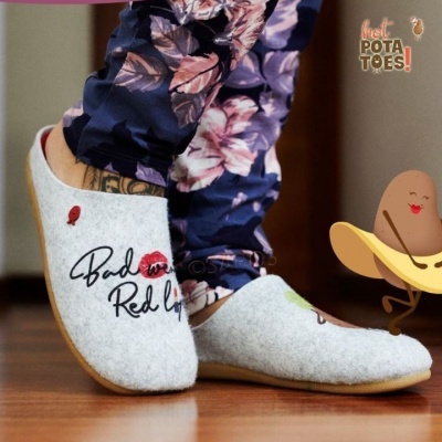 Chinelos de feltro cinzentos com bordados vermelhos e pretos usados com calças floridas