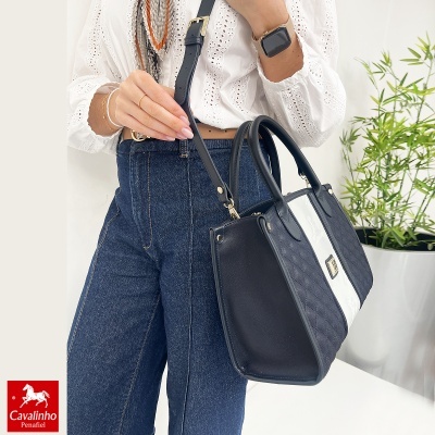 Mala de mãos preta com faixa branca e padrão matelassé, alça ajustável, usada com camisa branca e calças azuis.