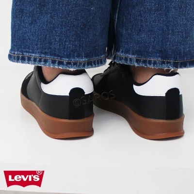 Ténis Levi's dourados e brancos com sola castanha usados com calças de ganga azul