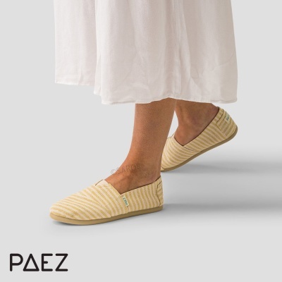 Alpargatas amarelas às riscas com etiqueta da marca Paez usadas por uma pessoa