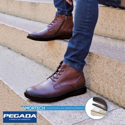 Botas castanhas de couro com atacadores e fecho, calçadas por pessoa em calças de ganga sentada em degraus de pedra.